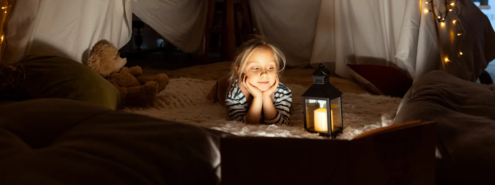 Liten flicka tältar inomhus med belysning