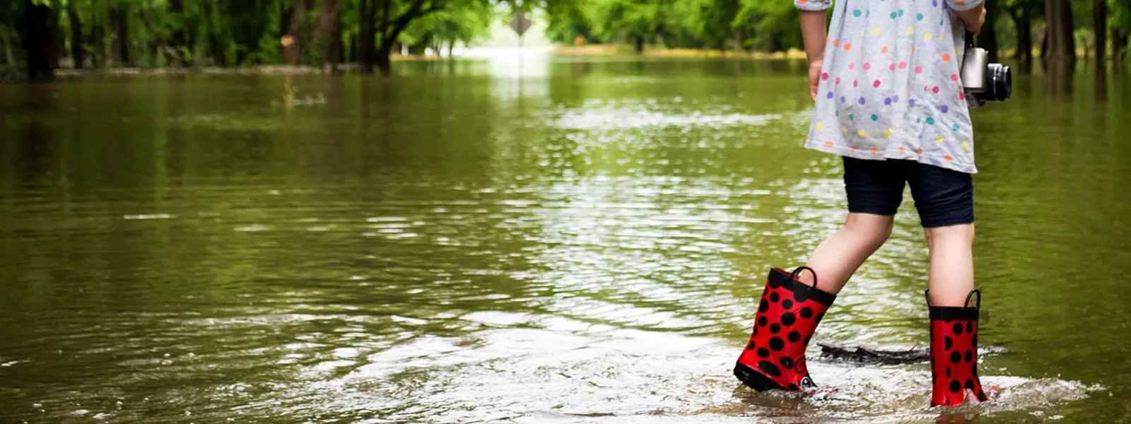 flicka i stövlar på vattenfylld väg