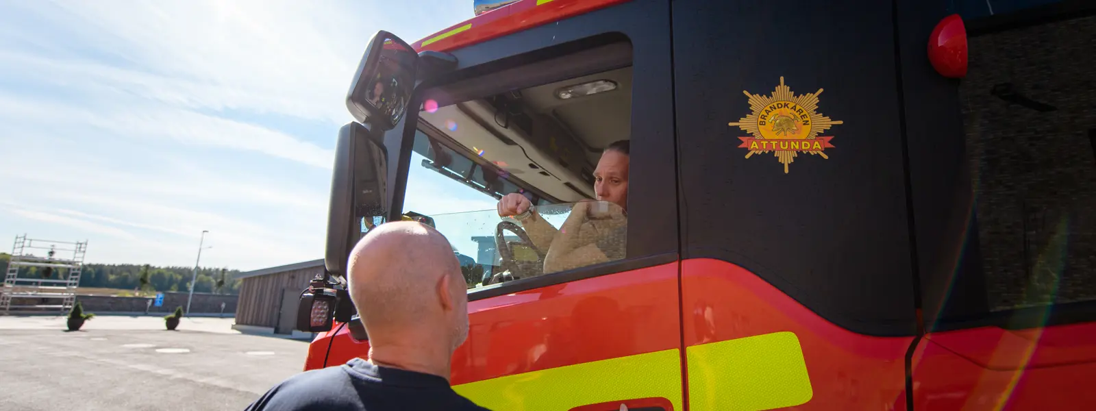 Brandman pratar med kvinna som kör brandbil
