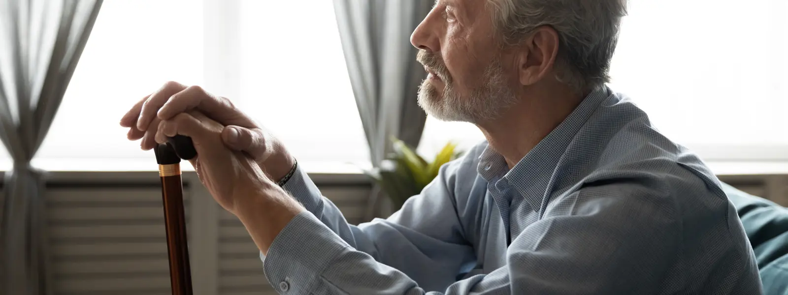 Äldre man med käpp sitter hemma