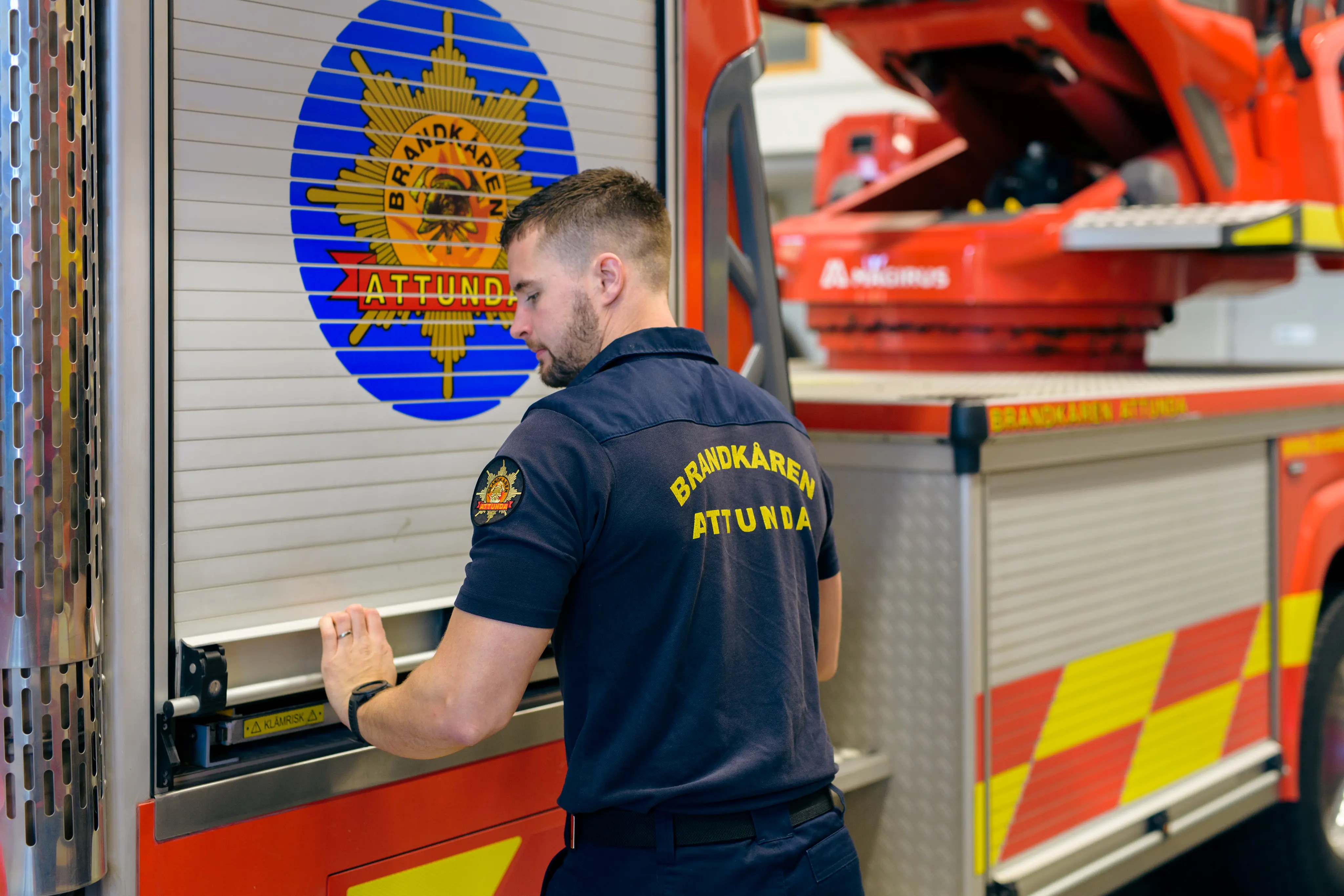 Brandman drar ner jalusiet på brandbilens sida